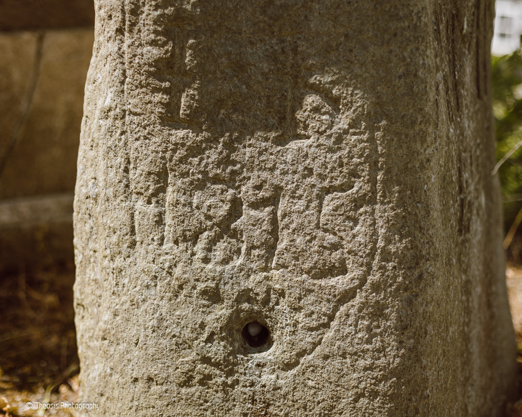 19th Century graffiti, and a hole drilled into the stone near the base.