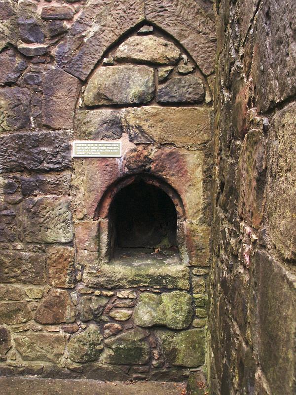 A doorway in the south wall of the basement, blocked up and converted to a cupboard.