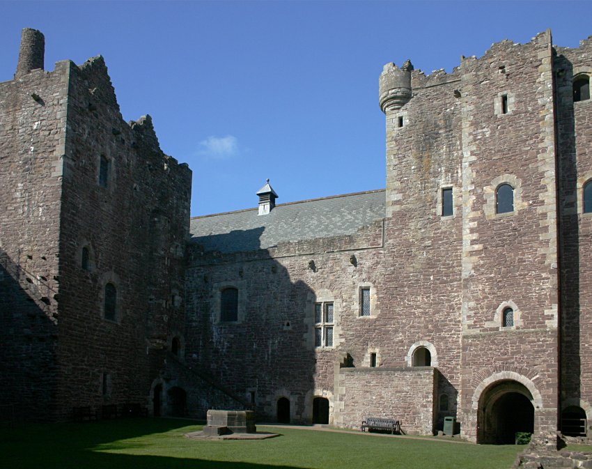 The gate tower (right), halls (centre) and kitchen tower (left) from the courtyard.  The well is in the foreground.