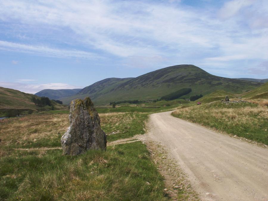 The standing stone, looking northeast along Glen Almond.  The cairn can be seen on the right where the road bends away.