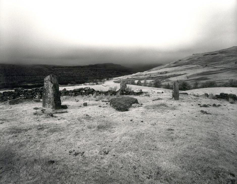 Looking north across the circle.  The shortest of the standing stones can be seen peeping over the wall just to the right of the nearest standing stone.