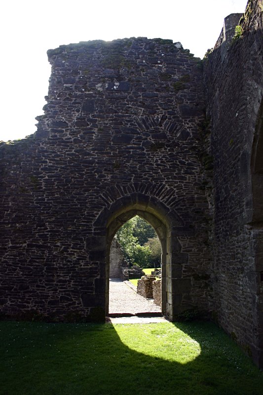 Looking from the nave back out to the west range.  Look at the arc of edge-on flat stones above the doorway.  Then look a little higher up the wall and slightly to the right.  There was clearly another opening there at one time.