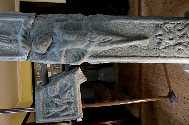 Front of the early stone crucifix, now protected inside the church.