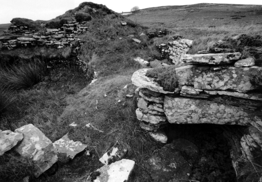 The broch wall.  To the left is the body of the broch.  Bottom right is a large void between the double walls, capped by large flat stones.